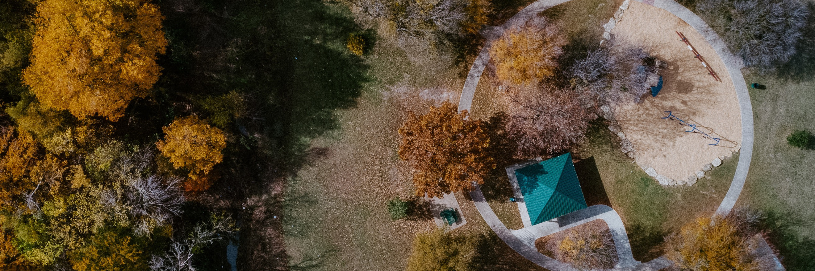 Aerial photo of Camelot Park during autumn with trees changing color and overhead view of covered pagoda.