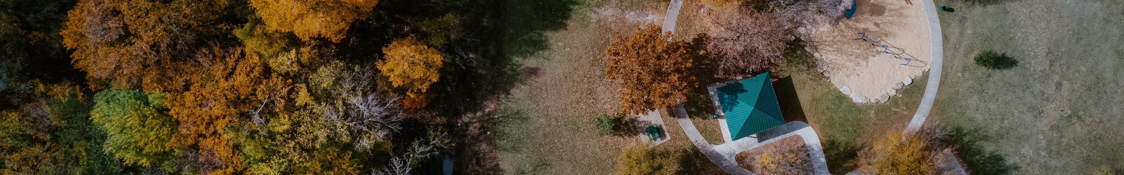 Aerial photo of Camelot Park during autumn with trees changing color and overhead view of covered pagoda.